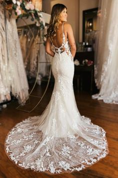 a woman in a white wedding dress standing on a wooden floor with her back to the camera