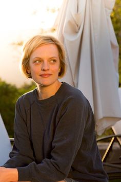 a woman sitting in front of an umbrella on a sunny day with her arms crossed