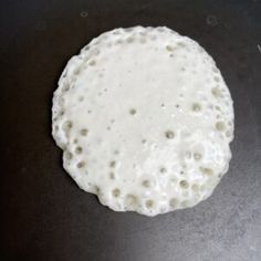 an uncooked pizza sitting on top of a black counter next to a frying pan