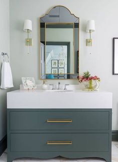 a bathroom vanity with two sinks and a large mirror above it, in front of a white wall