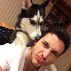 a man laying on top of a bed with a husky dog in front of him