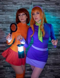 two women dressed up in costumes and holding magnifying glass with light shining on them