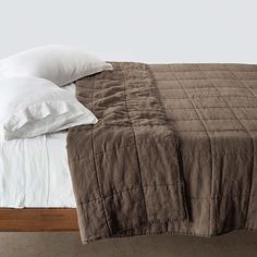 a bed with two pillows on top of it and a blanket over the headboard