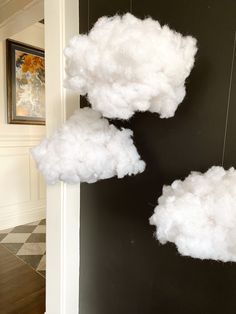 two white clouds hanging from the side of a black wall