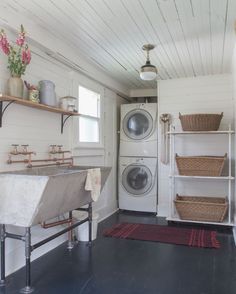 a washer and dryer in a small room with wood flooring on the walls