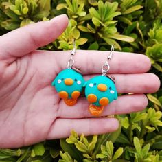 a pair of blue and orange earrings with polka dots on them sitting in a hand