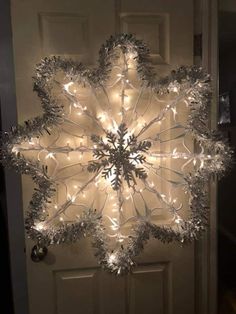 a lighted snowflake hanging from the side of a door with lights on it