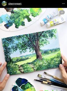 someone is painting a landscape with paintbrushes and watercolors