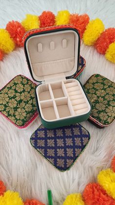 an open case sitting on top of a white fur covered floor next to colorful pom poms