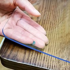 a person's hand on top of a table with a piece of blue tape