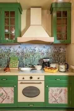 a kitchen with green cabinets and a white stove top oven in front of a wallpapered backsplash