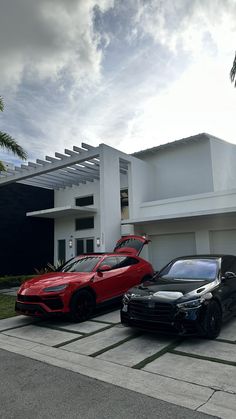 two cars parked next to each other in front of a white and black house with palm trees