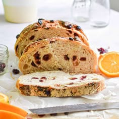 sliced loaf of bread sitting on top of a table next to oranges and a knife