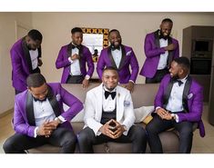 a group of men in purple and black suits sitting on top of a brown couch