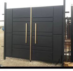 a large black gate with two gold handles on the front and side doors that are closed