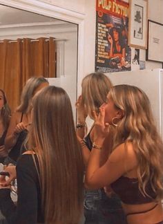 several women are standing in a room and one is brushing her teeth