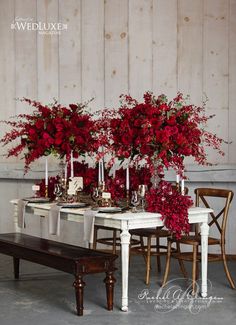 the table is set with red flowers and candles