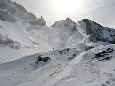 the sun shines brightly on some snow covered mountains and rocks in the foreground