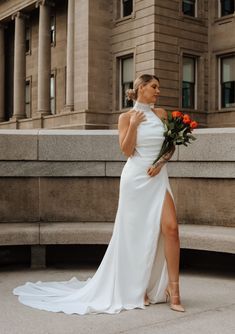 a woman in a white dress is standing on the steps with her legs crossed and flowers in her hand