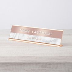 marble business name plate with rose gold border on white wooden background, mockup for product display