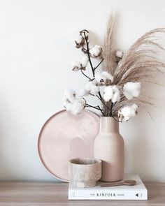 there is a vase with flowers in it and two cups on the table next to it