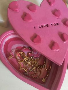 a pink heart shaped box filled with lots of small hearts and key chains in it