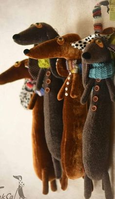 three stuffed dogs hanging on a wall with clothes pins attached to the dog's collars