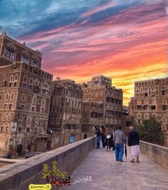 people walking across a bridge in the middle of a city at sunset or sunrise time