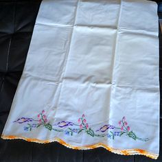 an embroidered tablecloth with flowers on it sitting on top of a black leather chair