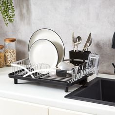 a dish rack with dishes and utensils on top of a kitchen countertop