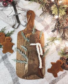 an old cutting board is decorated with gingerbreads and fir cones for the holiday season