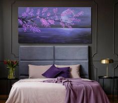 a bed with purple pillows and a painting on the wall above it that is in a bedroom