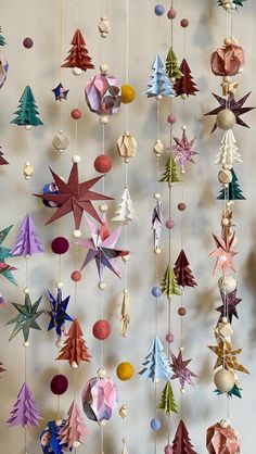 an origami christmas tree mobile hanging from strings with balls and ornaments on it