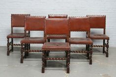 four brown leather chairs sitting next to each other