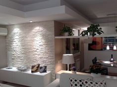 a living room filled with furniture and a white brick wall mounted on the side of it