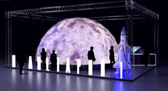 people are standing in front of a large display with the moon on it's side