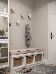 a white entryway with several baskets on the floor and a coat rack above it