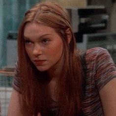 a woman with long red hair sitting at a table