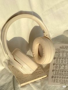 a pair of headphones sitting on top of a book next to an open sheet of paper