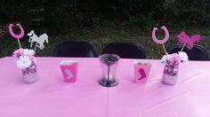 pink table cloth topped with vases filled with flowers and paper cutouts on top of it