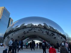 many people are walking around in front of the cloud gate sculpture at millennium park, chicago