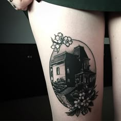 a woman's thigh with a house and flowers on it