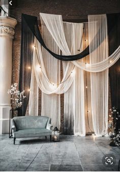 a room decorated with sheer curtains, candles and a blue chair in front of it