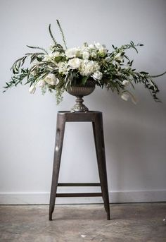 a vase with white flowers sitting on top of a wooden stool