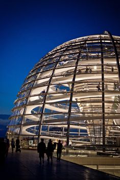 people are walking around in front of a dome structure at night with the lights on