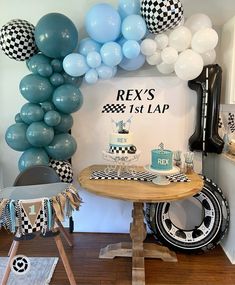 a table with balloons and cake on it in front of a sign that says rex's 1st lap