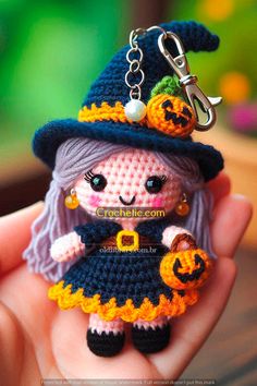 a small doll wearing a witches hat and holding a pumpkin keychain in her hand