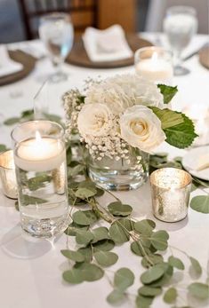 white flowers and greenery are arranged on the table for a wedding centerpieces