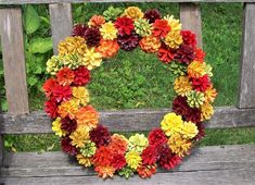 a wreath made out of flowers sitting on top of a wooden bench