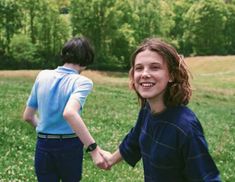 two young children holding hands in a field